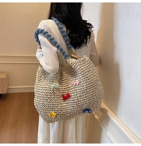 Close-up of woven straw tote bag featuring colorful crochet bows and blue ruffled straps