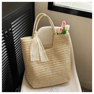 Detail of hand-woven straw tote with elegant white lace bow on a white chair