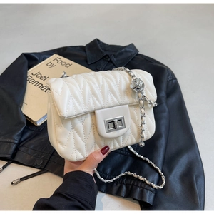 Close-up of white quilted faux leather bag with silver twist lock and metal ball chain