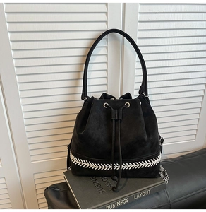 Dettaglio borsa a secchiello in pelle scamosciata nera con ricamo bianco e chiusura a coulisse