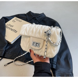 Close-up of white quilted leather bag with silver twist lock and chain strap details