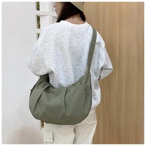 Nylon dumpling bag in army green shown on shoulder with minimalist lifestyle aesthetics