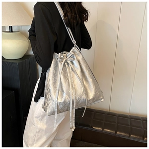Detailed close-up of metallic silver drawstring bucket bag with crinkle texture and bow