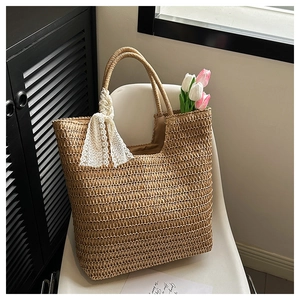 Close-up of woven straw tote bag featuring white lace ribbon and fresh tulips