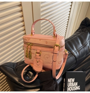 Detail of pink small square crossbody bag with embossed patterns and gold hardware