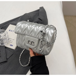 Macro detail of silver crossbody bag with chevron quilting and metal twist lock