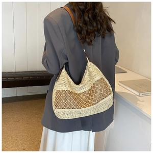Detail of woven straw hobo bag with brown leather strap and intricate hollow mesh design