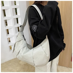 Detail of light grey pleated half-moon crossbody bag with wide strap on model