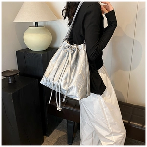 Detail of silver metallic bucket bag with drawstring closure and bow accent in modern style
