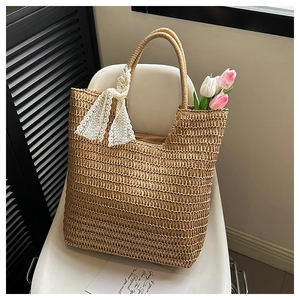 Detail of hand-woven straw tote bag with white lace ribbon on a minimalist chair