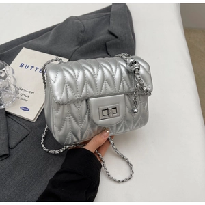 Macro detail of silver quilted small square bag with chain strap and metallic buckle