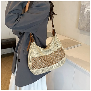 Detail view of woven straw shoulder bag with large mesh pattern and brown leather strap