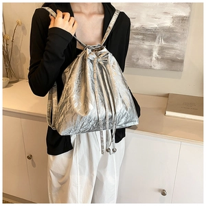 Detail of silver metallic drawstring bucket bag with pleated texture on a model
