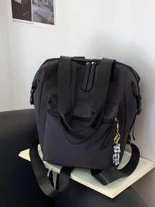 Mochila ligera de nailon negro con colgante de oso sobre fondo de libro abierto