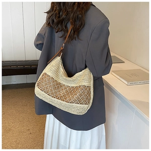 Detail of a large straw shoulder bag with adjustable brown leather strap for summer