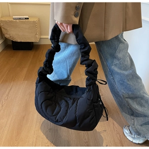 Detail of black quilted puffer bag with scrunchie handle and drawstring design