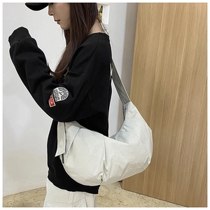 Detail view of the large white crescent dumpling bag showing durable nylon material on model