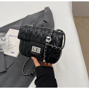 Close-up of black quilted flap bag with silver sphere chain and twist lock detail