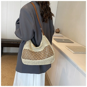 Detail of hobo beach bag showing mesh straw weave and brown leather strap texture