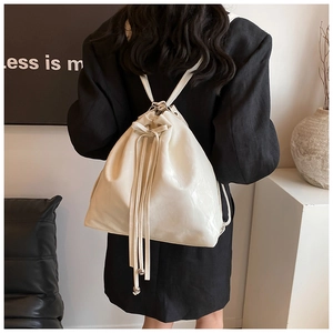 Detail of cream white bucket backpack with bow drawstring and silver metal beads