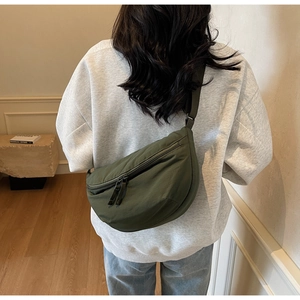 Detail view of deep green nylon dumpling bag with adjustable strap and double zipper