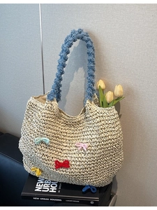 Handwoven straw tote bag with colorful knitted bows and blue plush handles for beach vacation
