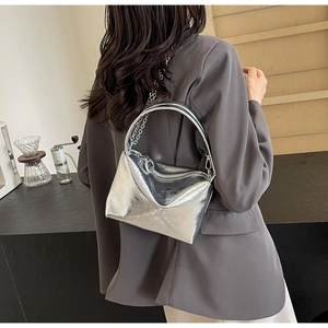Detail view of stylish silver metallic crossbody bag with chain strap and leather handle
