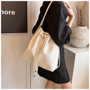Lifestyle shot of a white drawstring bucket bag with tassel details on a model