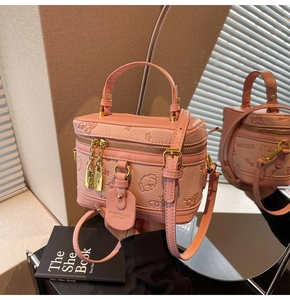 Detailed close-up of a pink embossed box bag with gold chain and brand tag shown by hand