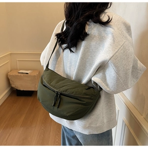 Detailed view of the dark green crescent nylon crossbody bag on a model's shoulder