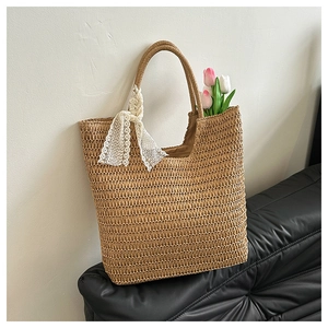 Detailed macro view of woven straw tote bag featuring a decorative white lace bow