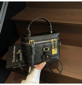 Detail of black pebbled leather box bag featuring butterfly embossing and golden charm
