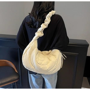 Detail of off-white quilted nylon bag featuring pleated ruffled straps and drawstring sides