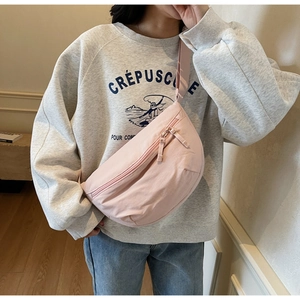 Detail showing the light pink crescent crossbody bag with matching dual zippers