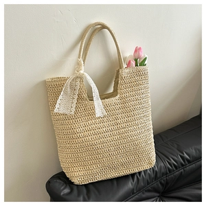 Close-up of woven straw tote bag with delicate white lace ribbon and tulip detail