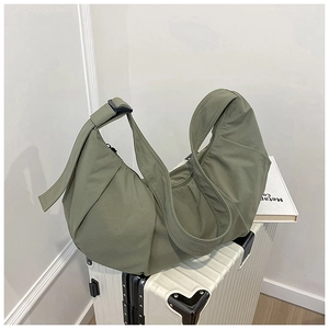 Detail of olive green nylon dumpling bag with pleated texture on white suitcase