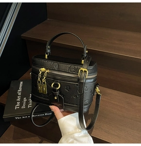 Detailed macro view of black embossed floral leather box bag with gold metal hardware