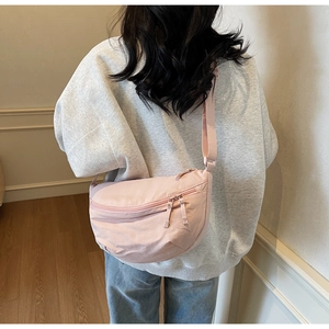 Model wearing a light pink nylon dumpling bag with adjustable shoulder strap