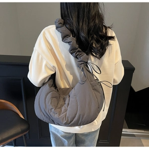 Detail of grey quilted crescent shoulder bag featuring pleated drawstring and bow strap