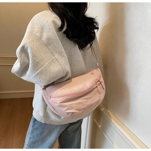 Detail of a pink nylon crescent bag with dual zippers and soft matte texture finish