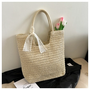 Detail einer geflochtenen Strohtasche mit dekorativer Spitzenschleife und rosa Tulpen