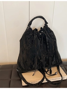 Glossy black drawstring bucket bag with chain texture and elegant leather handle
