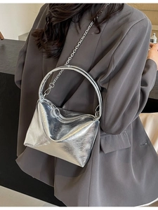 Silver metallic bucket bag with chain strap styled on model wearing a grey blazer
