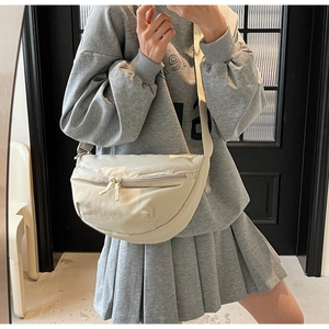 Close-up of beige crescent canvas bag with dual zippers and adjustable wide strap
