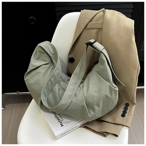 Detail of light green ruched hobo bag with adjustable strap on minimalist chair