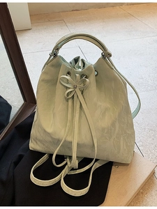 Light green and beige textured leather bucket bag with drawstring bow and dual straps