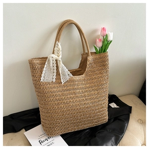 Detail der gewebten Strohtasche mit eleganter weißer Spitzenschleife auf Lederhintergrund