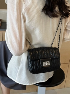 Quilted black chain crossbody bag for women with silver buckle on a stylish model