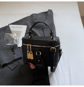 Detail of black embossed crossbody bag with gold hardware and dual zipper closure