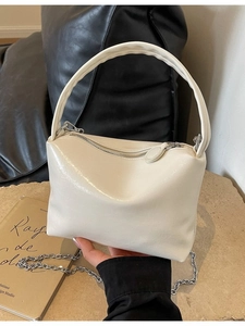 Elegant cream glossy faux leather shoulder bag with silver chain strap shown in a hand